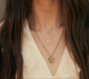 Woman wearing gold necklaces with a neutral background